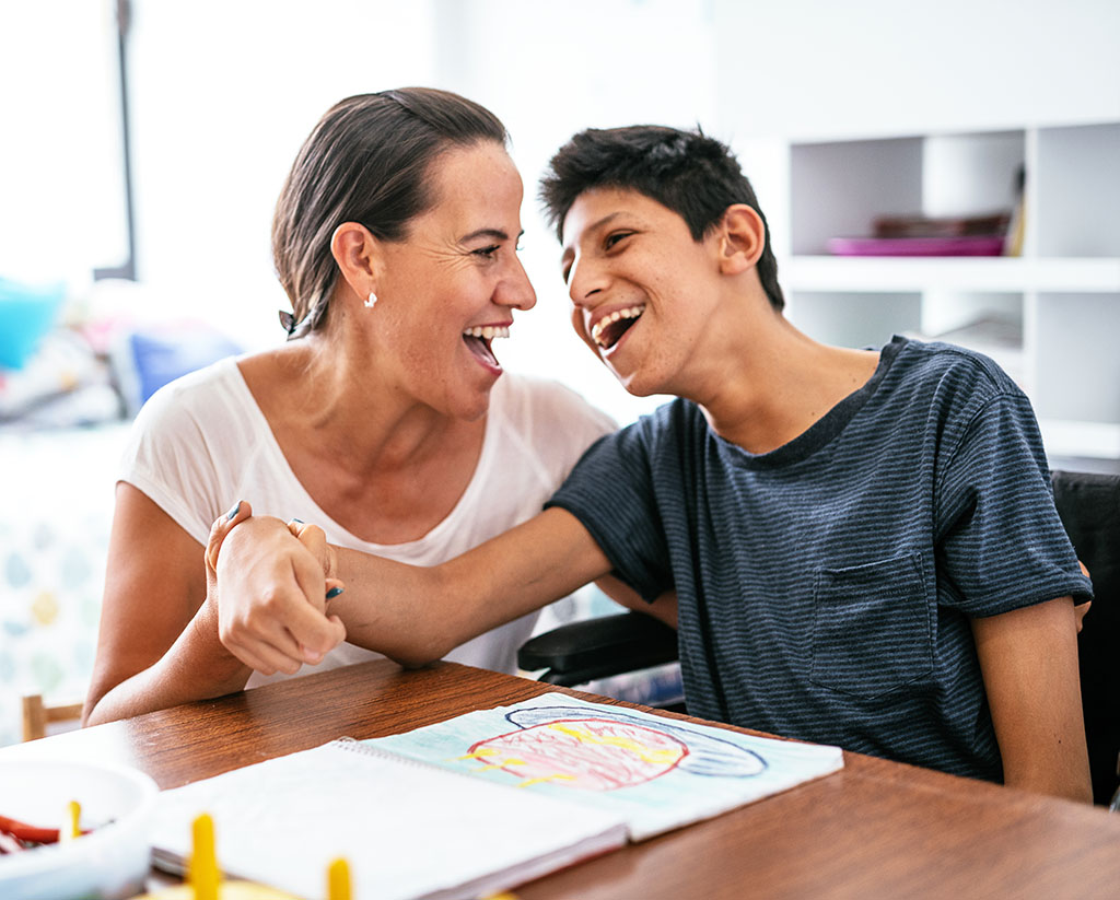 Disabled Latino teenager with Celebral Palsy and mother laughing.
